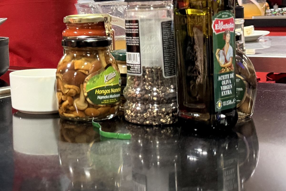 Frasco de hongos nameko Killio’s junto a un molino de pimienta y una botella de aceite La Española.